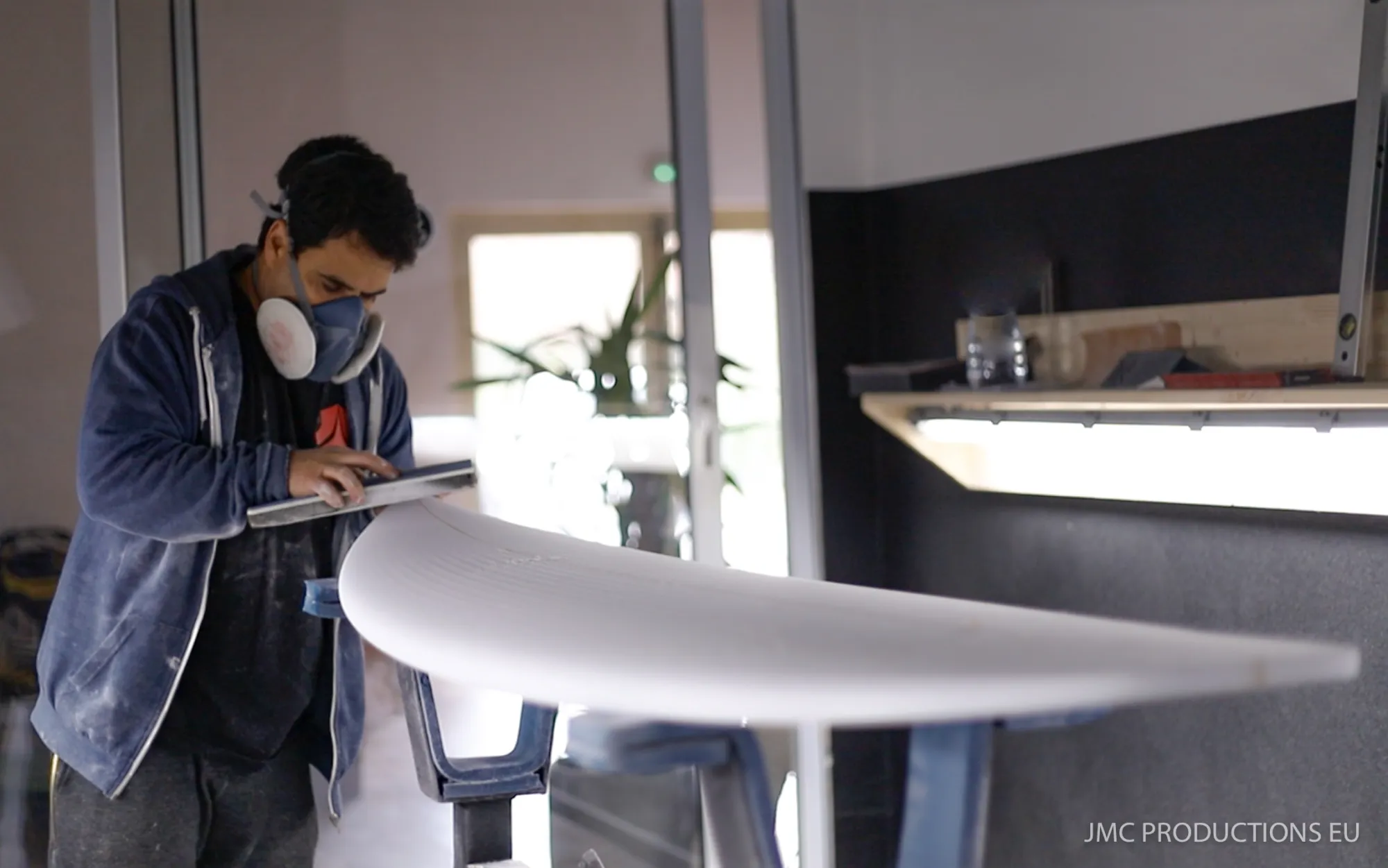 Alessandro Pierre vérifiant le profil d'une planche de surf dans la shape room