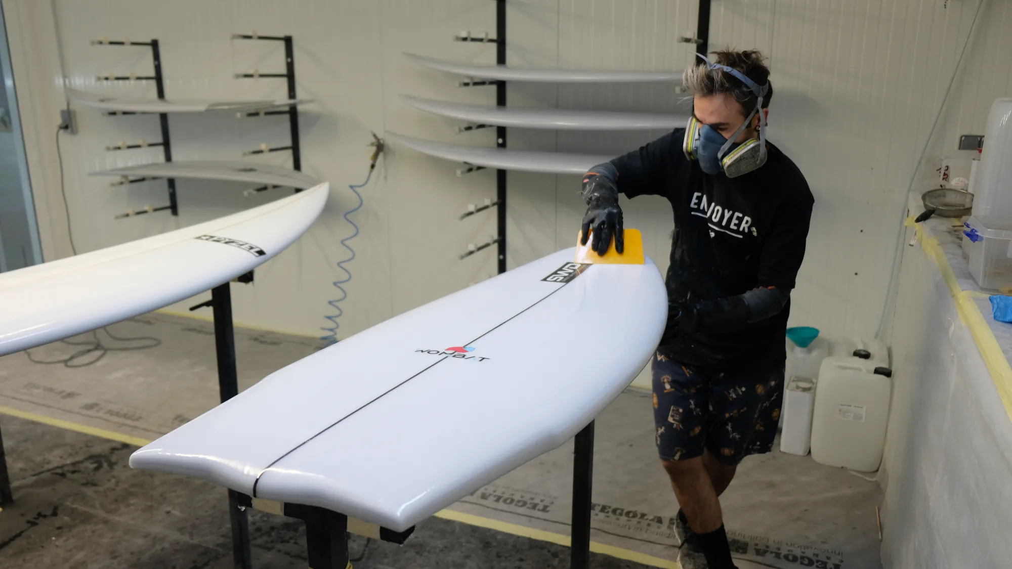 Alessandro Pierre contrôlant la finition d'une planche de surf