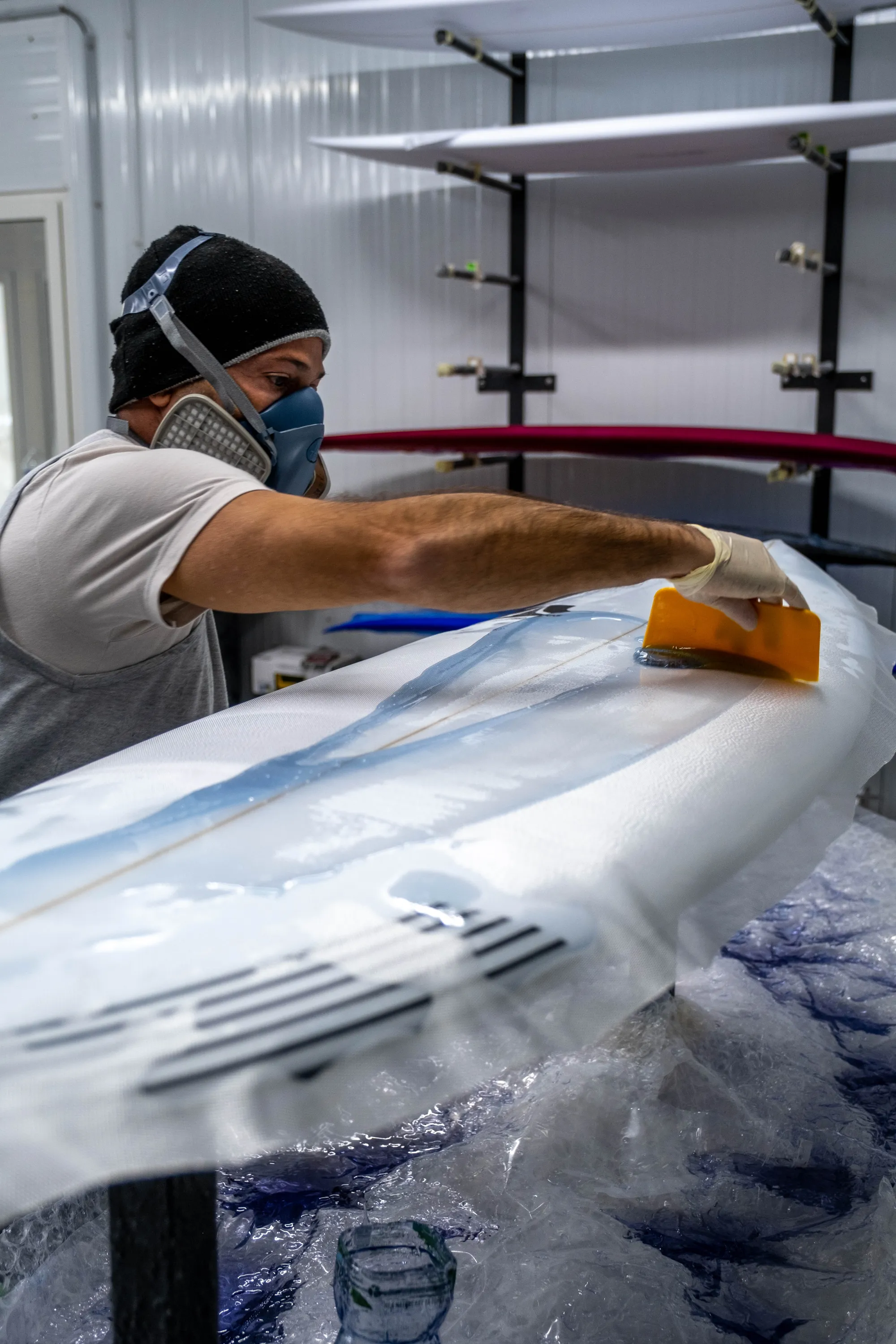 Alessandro Pierre laminant la résine sur une planche custom avec raclette