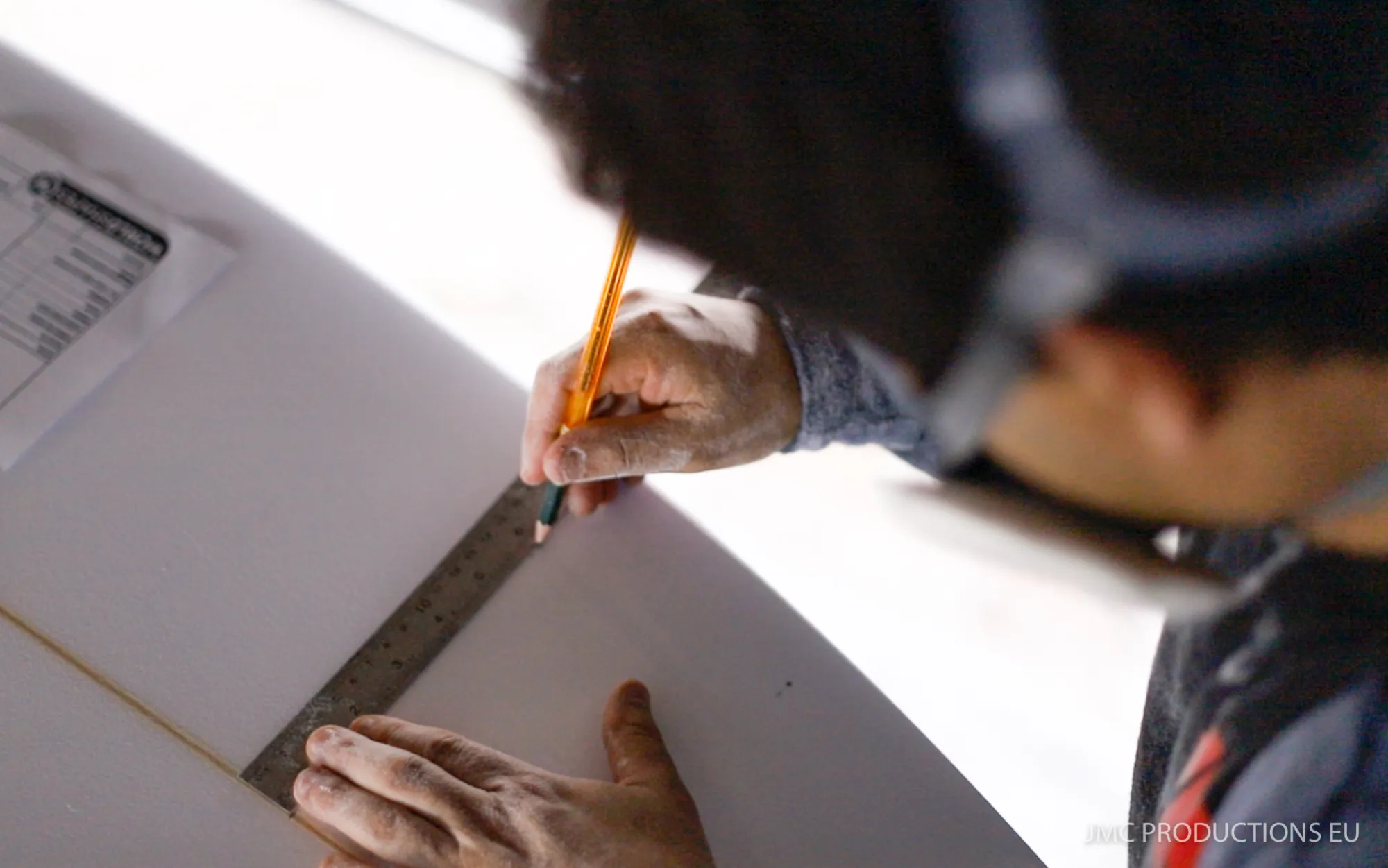Alessandro Pierre traçant les dimensions d'une planche avec règle et crayon