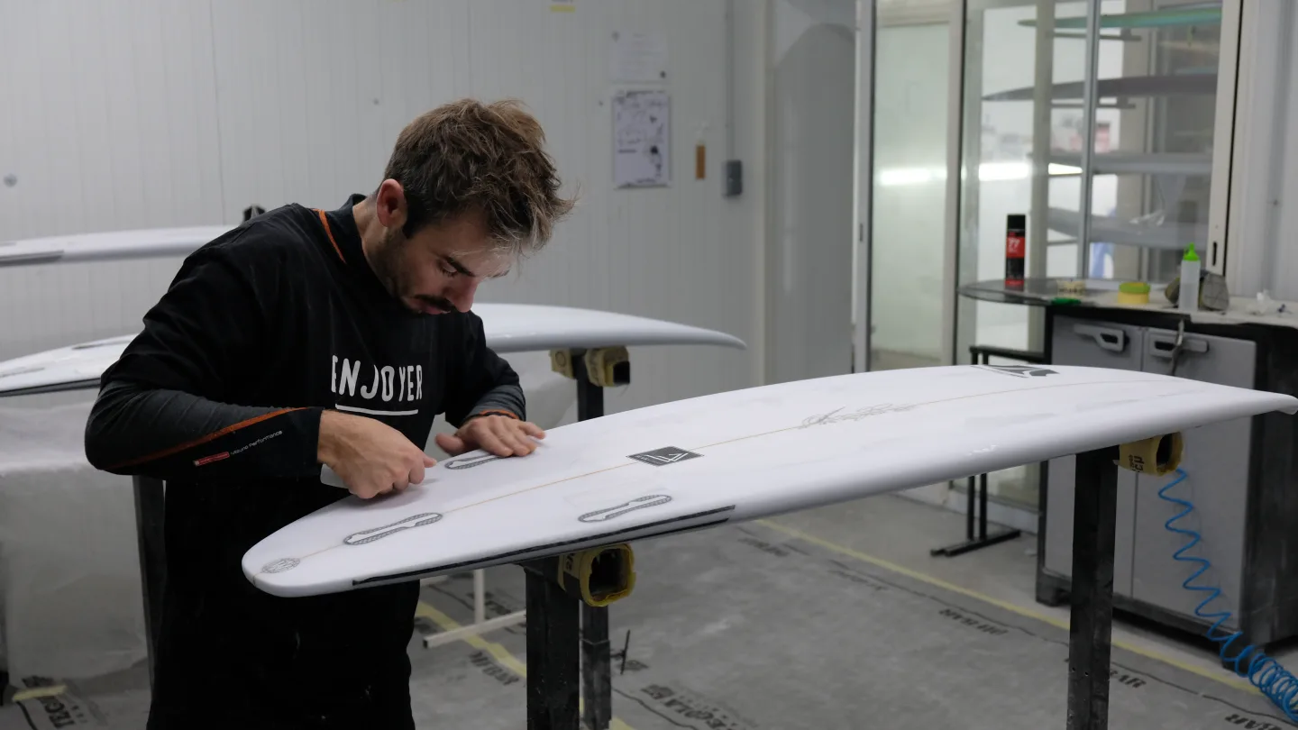 Alessandro Pierre posant les stickers et logos sur une planche finie